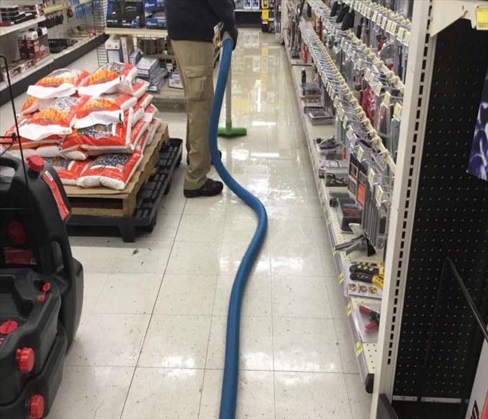 technician vacuuming up the standing water same location in the store