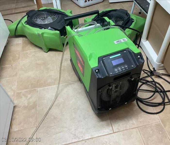 SERVPRO air movers and a dehumidifier operating on a laundry room floor