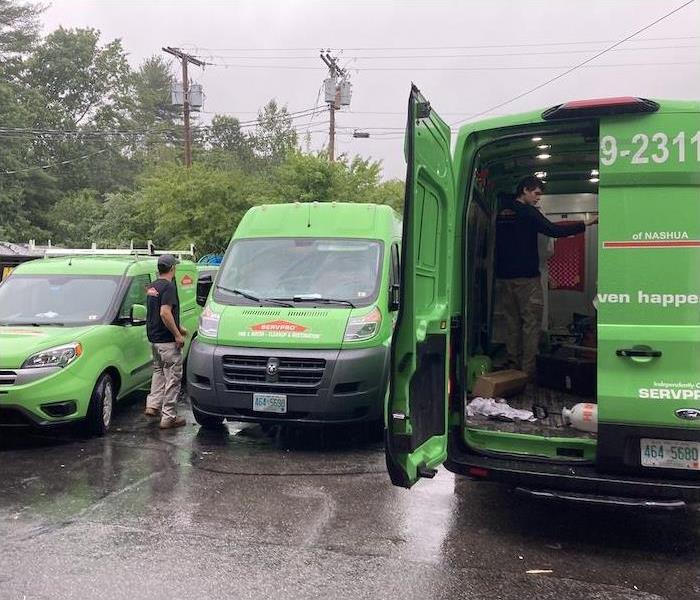 Three SERVPRO vehicles being loaded by technicians in a parking lot